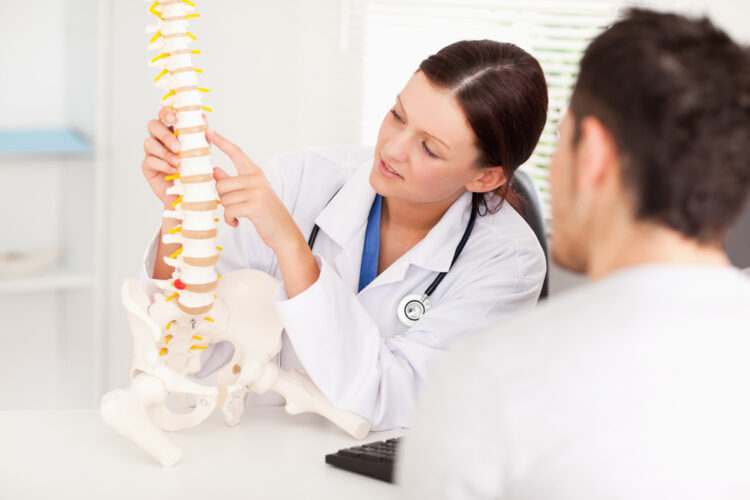 Doctor showing patient model of the spine